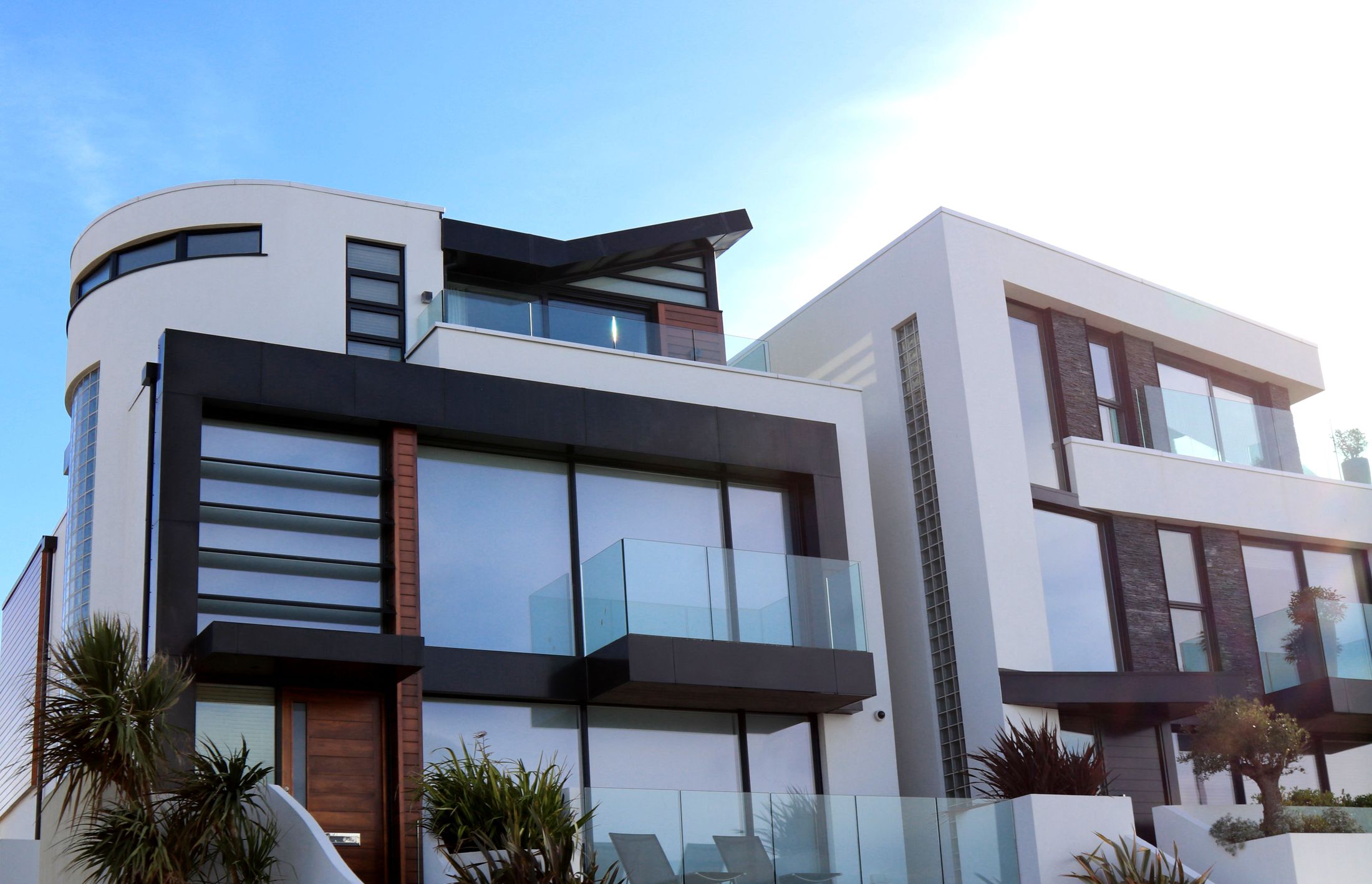 A contemporary home with sculptural white walls, timber accents, and glass balconies